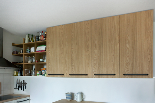 Kitchen cupboard and shelves made from oak covered mdf with metal handles.